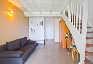 Una sala de estar moderna con un sofá, una escalera y una puerta que da a otra habitación.