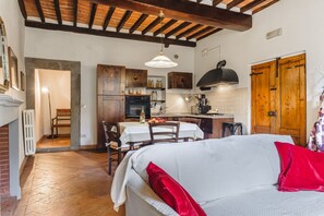 A cozy interior with a dining area, kitchen, and a bed with red pillows. - Casa Teresa - Authentic Tuscan Charm in the Heart of Cortona (Cortona)
