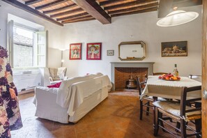 A room with a fireplace, a dining table with fruit, and artwork on the walls. - Casa Teresa - Authentic Tuscan Charm in the Heart of Cortona (Cortona)