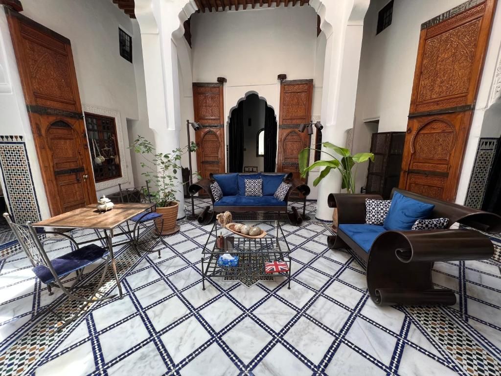 Un patio interior con suelo de baldosas, una mesa de madera, dos sofás y una planta en maceta.