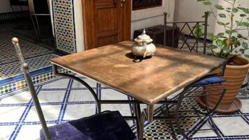 A dining table with a vintage design, a blue cushioned chair, and a potted plant.