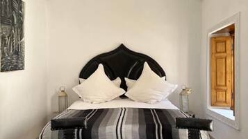 A room with a bed, a small round table, and a window.