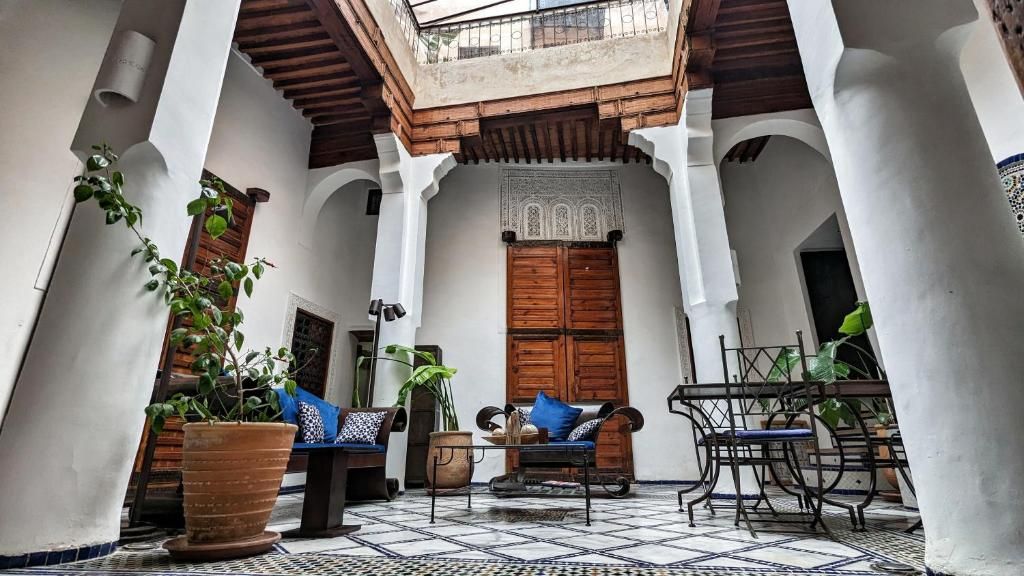 Un patio con un banco de madera, plantas en macetas y suelo de baldosas.