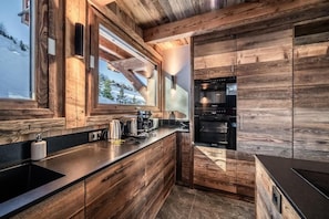 A modern kitchen with wooden cabinetry and a large window. - Luxury Mountain Chalet with Jacuzzi, Sauna & Hammam near Mont Blanc (Saint-Gervais-les-Bains)