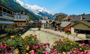 A town with buildings and a river, with mountains in the background. - Luxury Mountain Chalet with Jacuzzi, Sauna & Hammam near Mont Blanc (Saint-Gervais-les-Bains)