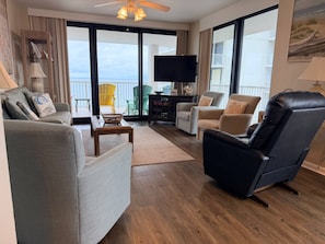 A spacious living area with a sofa, armchair, and a flat-screen TV on a stand. - Summer House 1006A (Orange Beach)
