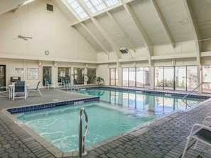An indoor swimming pool with a tiled edge, a metal ladder, and a ceiling fan. - Summer House 1006A (Orange Beach)