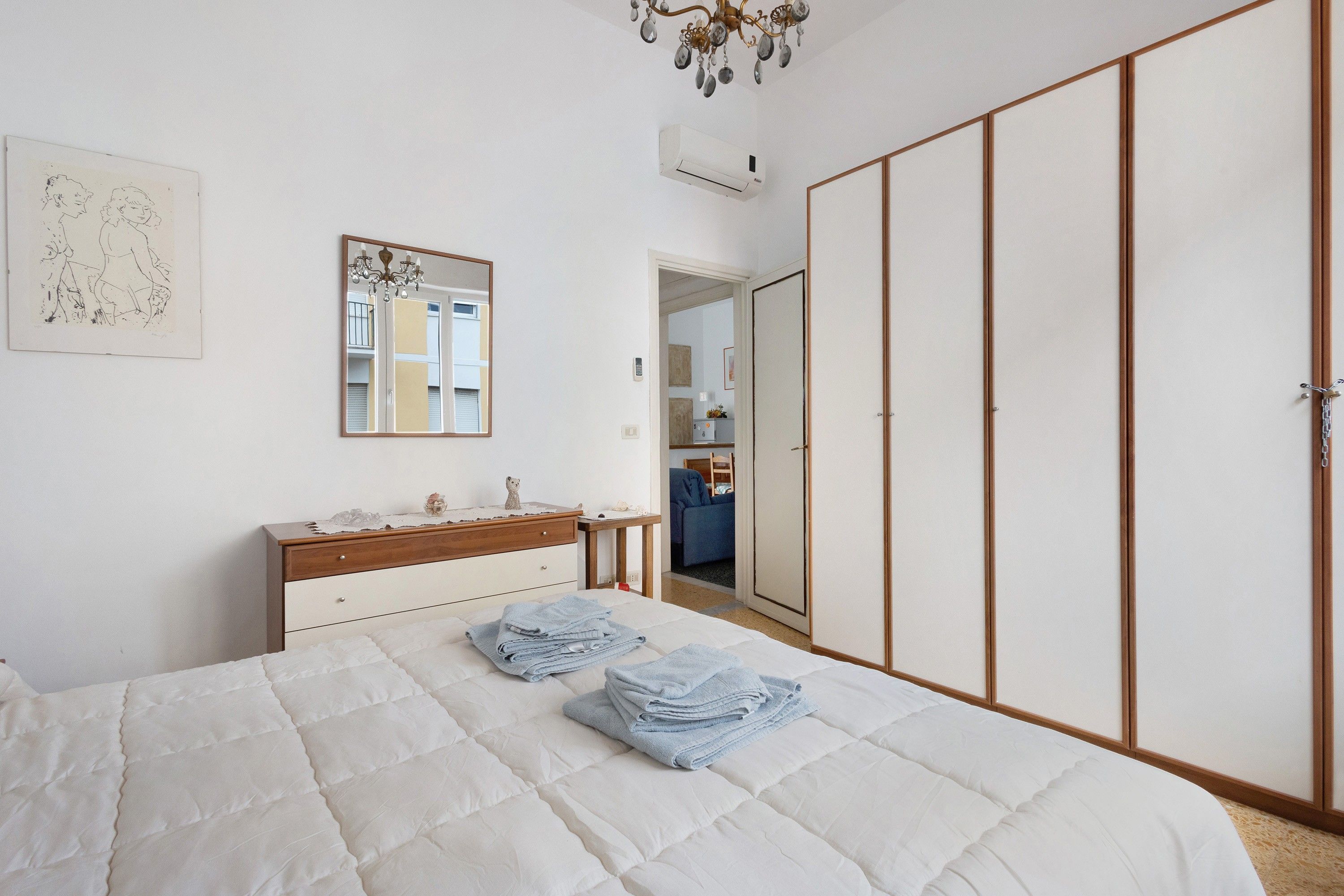 Un dormitorio con cama, cómoda, espejo, armario y candelabro.