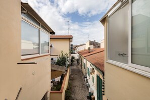 A narrow alleyway between buildings with tiled roofs, a visible laundry line, and a clear sky. - Apartment 'Casa Glad' with Balcony and Air Conditioning (Viareggio)