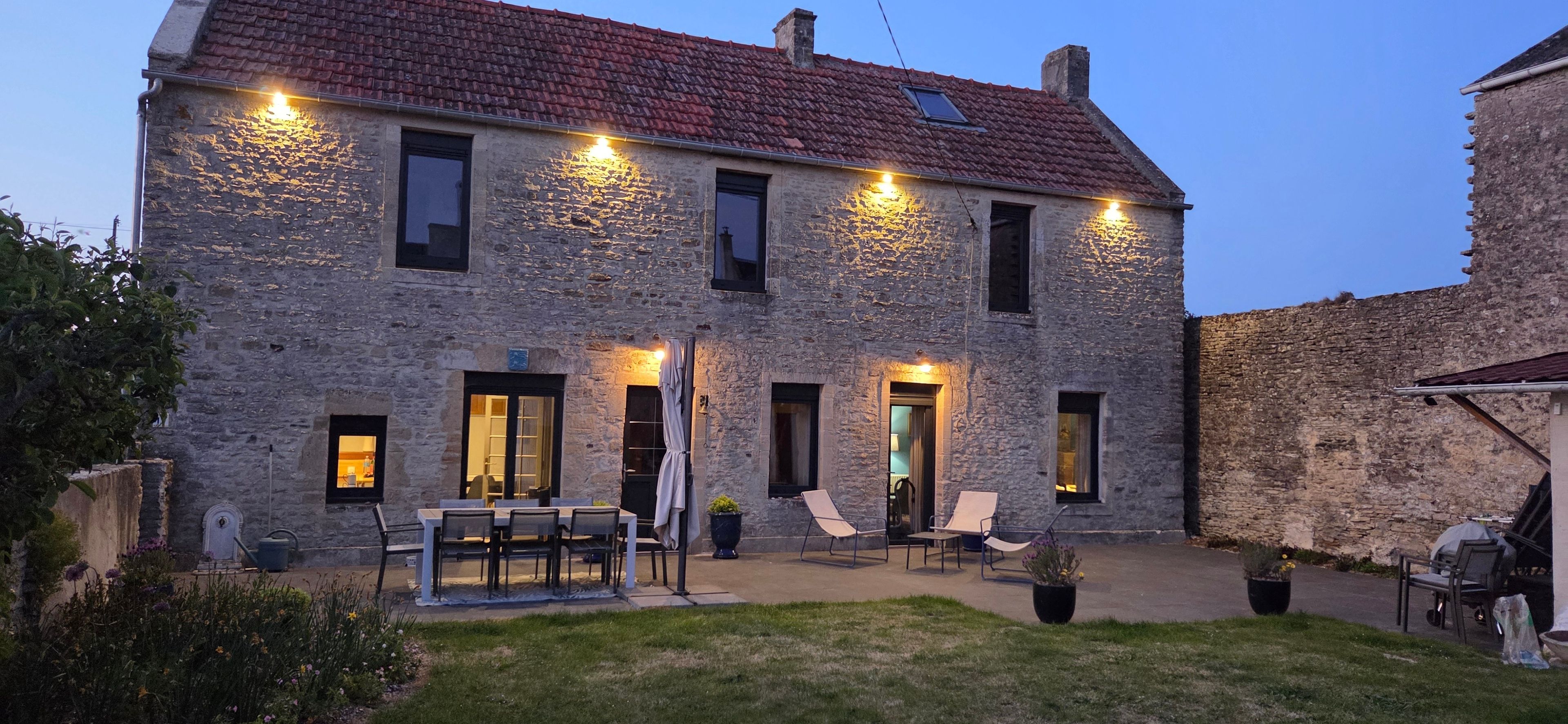 Un edificio in pietra con tetto in tegole, posti a sedere all'aperto e un ingresso ben illuminato.