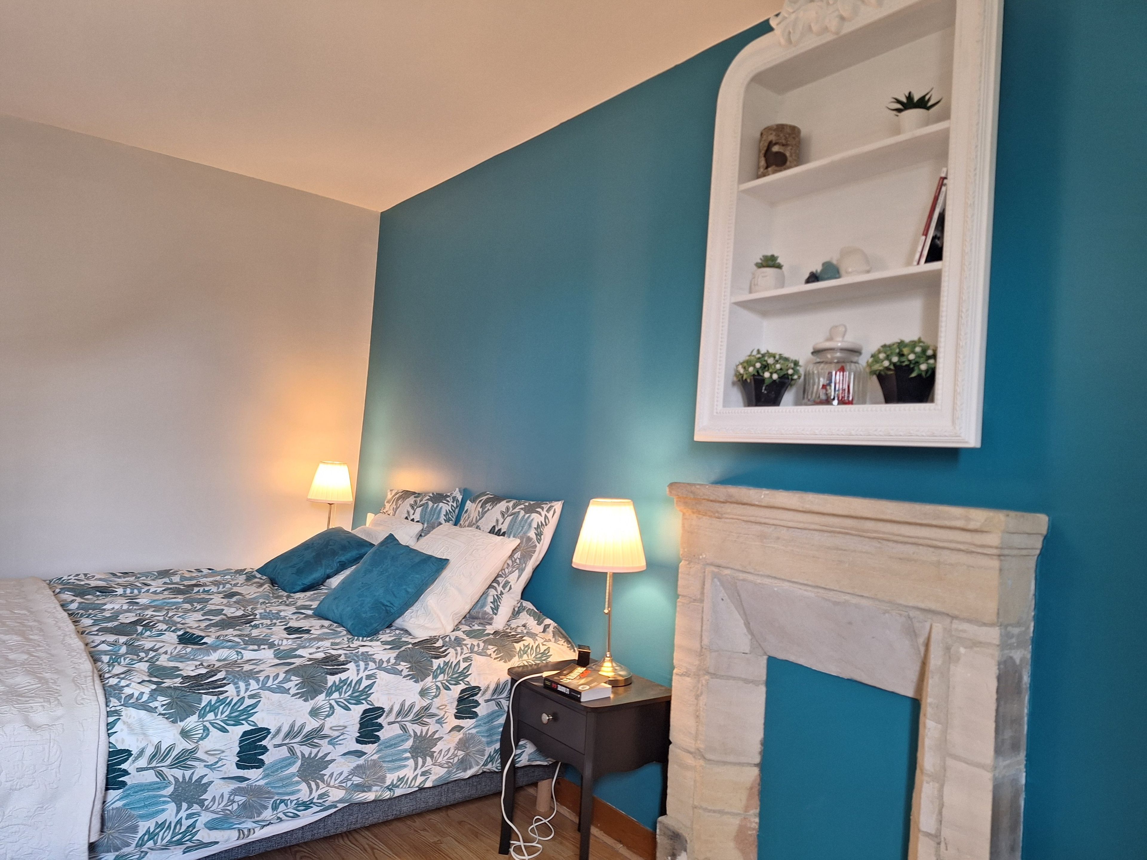 Ein Schlafzimmer mit einem Bett, Nachttischlampen, einem Kamin und einem Regal mit Dekorationen.