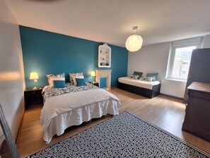 A bedroom with a bed, bedside tables, a fireplace, and a window.
