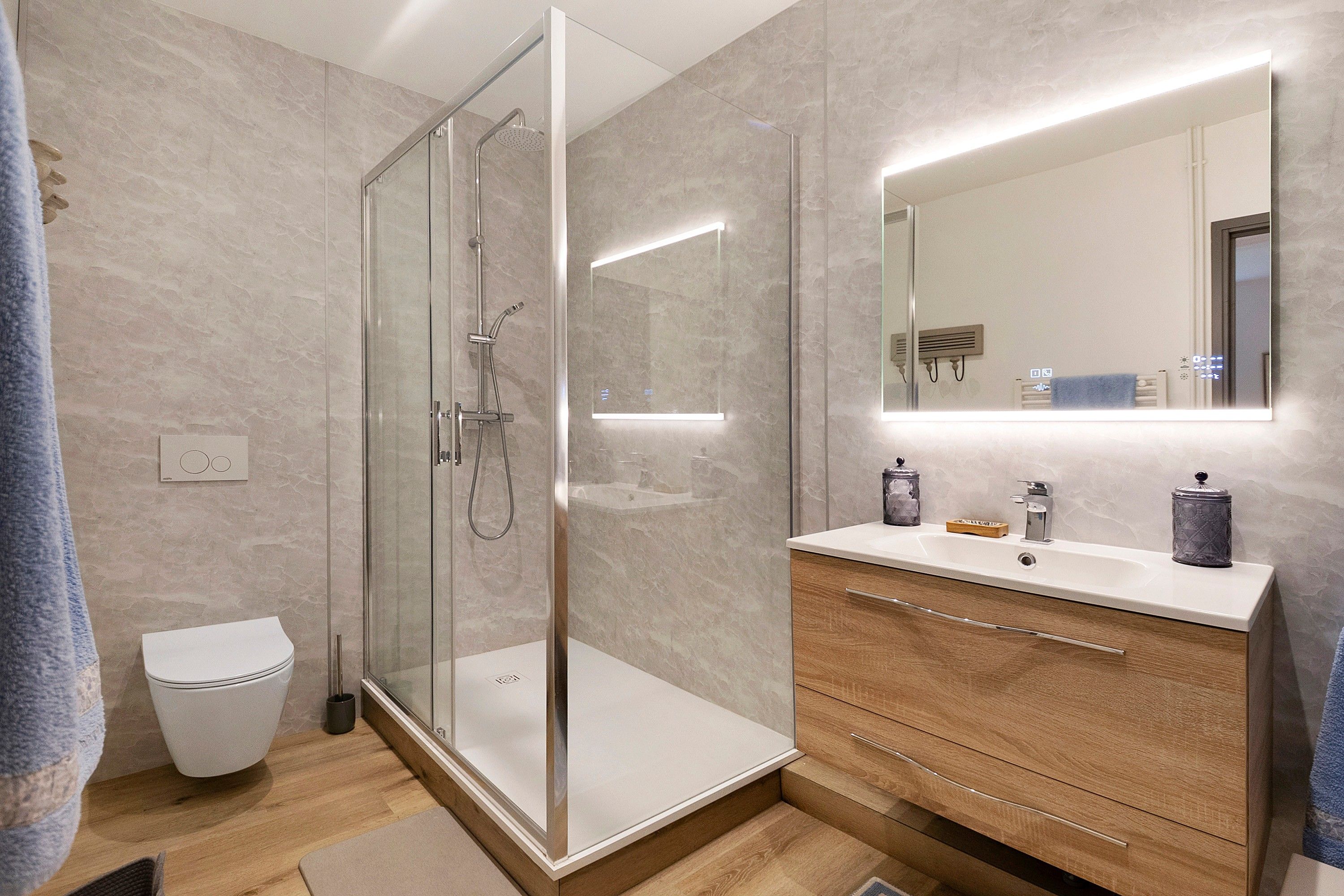 Ein modernes Badezimmer mit einer Duschkabine, einem Waschtisch mit Spiegel und einer Toilette.