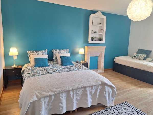 A bedroom with a large bed, a smaller bed, a fireplace, and a nightstand with a lamp. - Holiday Home 'Longues Amarres' with Terrace, Garden and Wi-Fi (Longues-sur-Mer)