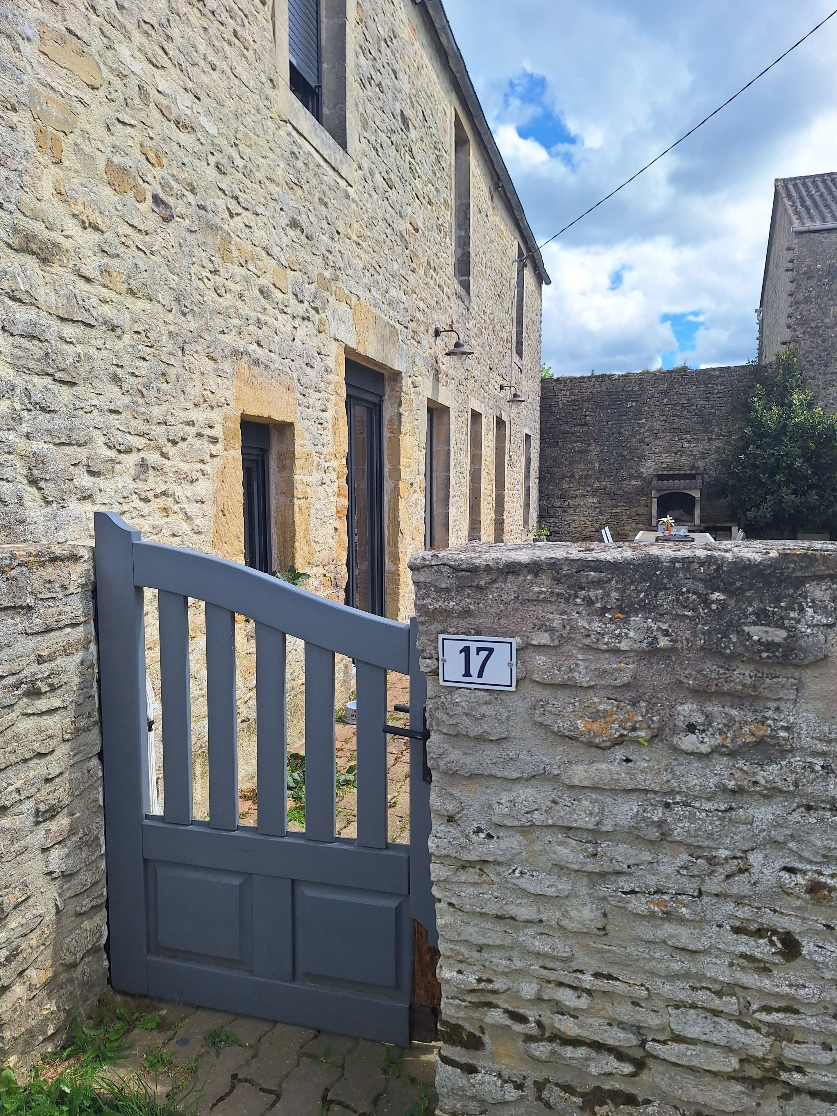 Un bâtiment en pierre avec une plaque numérotée, une entrée fermée par un portail et une cour intérieure.
