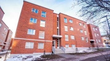 En byggnad i flera vÄningar, byggd av tegel, med en central trappa, fönster och en liten trÀdgÄrdsyta.