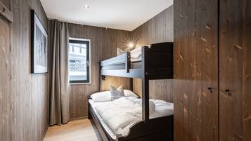Een kamer met een stapelbed, houten wanden, een raam met gordijnen en een lijst met een foto aan de muur.