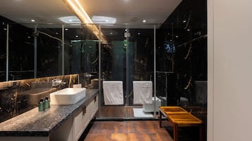 A modern bathroom with a marble vanity, a glass shower enclosure, and a wooden bench.