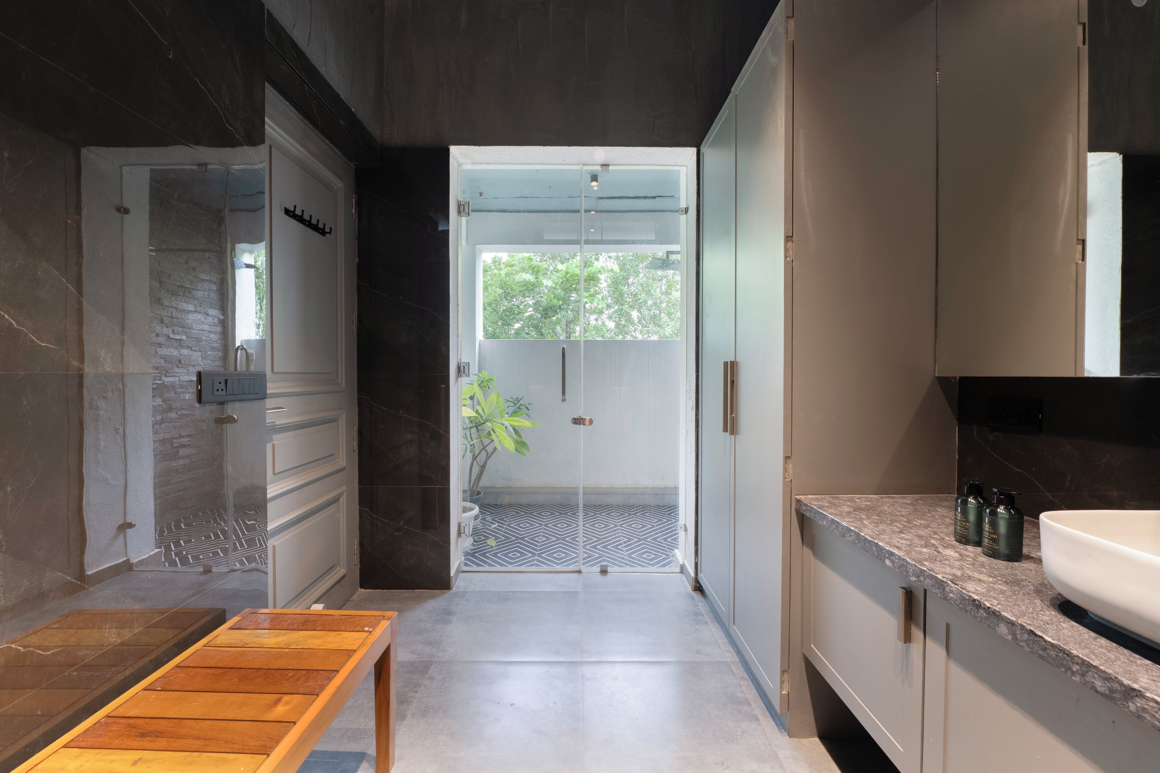 A modern bathroom with a shower, a sink, and a bench.