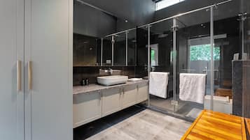 Uma casa de banho moderna com um espelho grande, uma pia e uma área de duche.