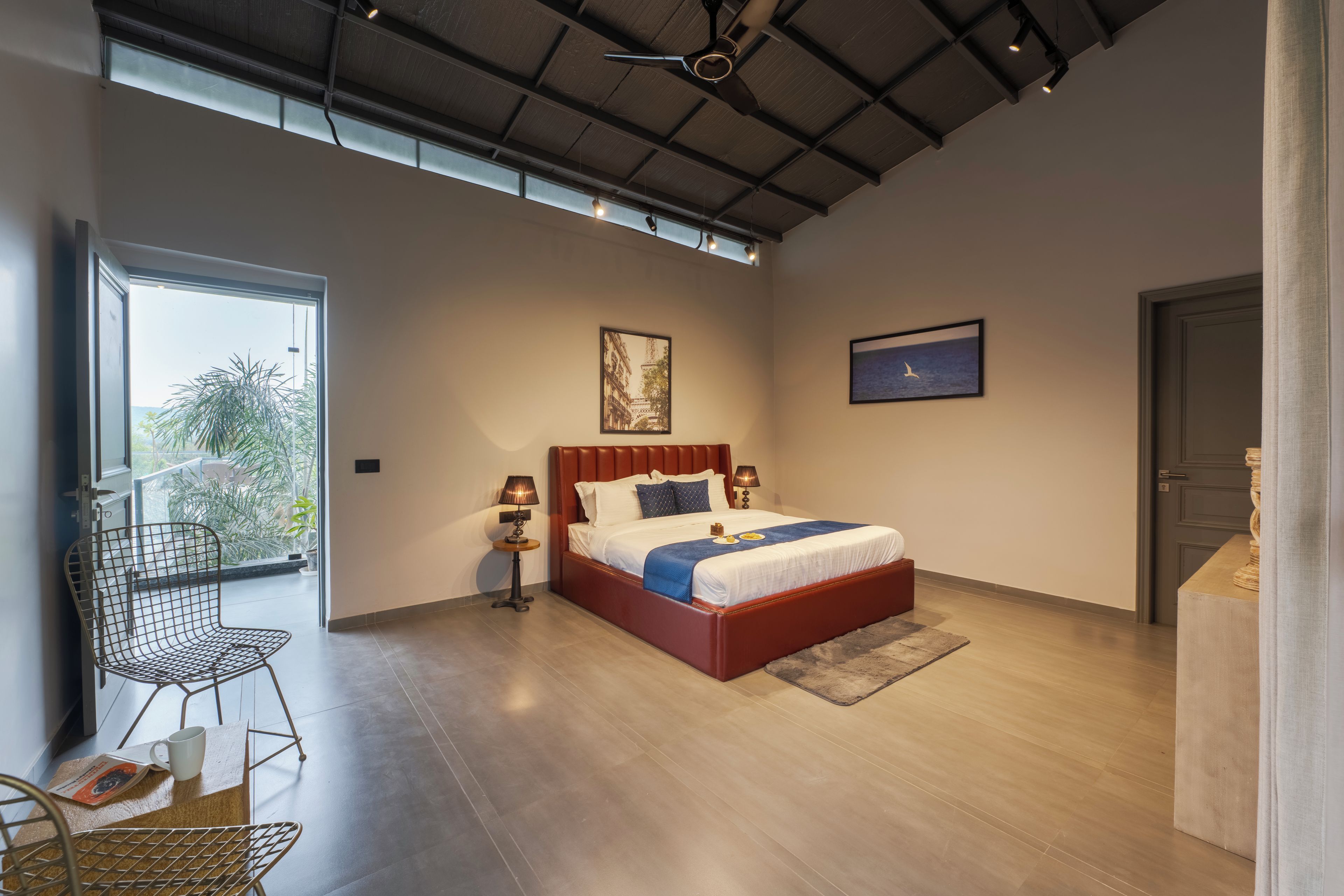 A modern bedroom with a large bed, a desk, and a chair.