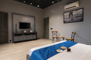 Una habitació d'hotel amb un llit, una televisió de pantalla plana, una taula de treball, dues cadires i un quadre a la paret.