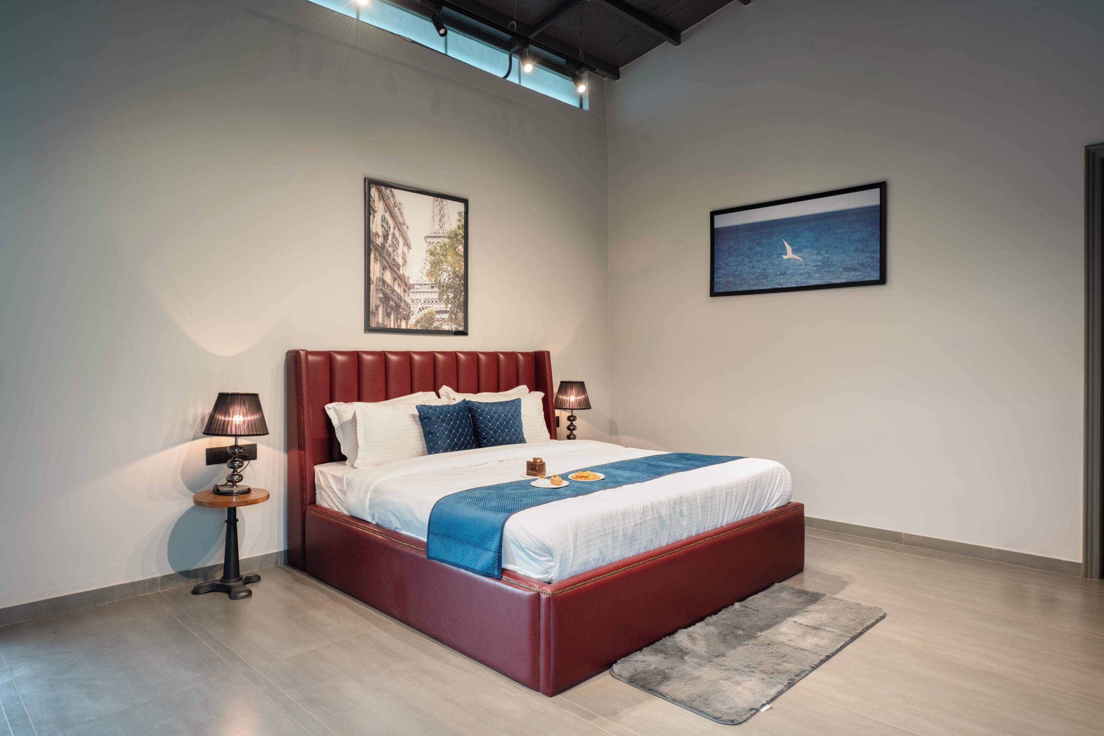 Quarto moderno com uma cama grande, duas mesas de cabeceira e obras de arte nas paredes.