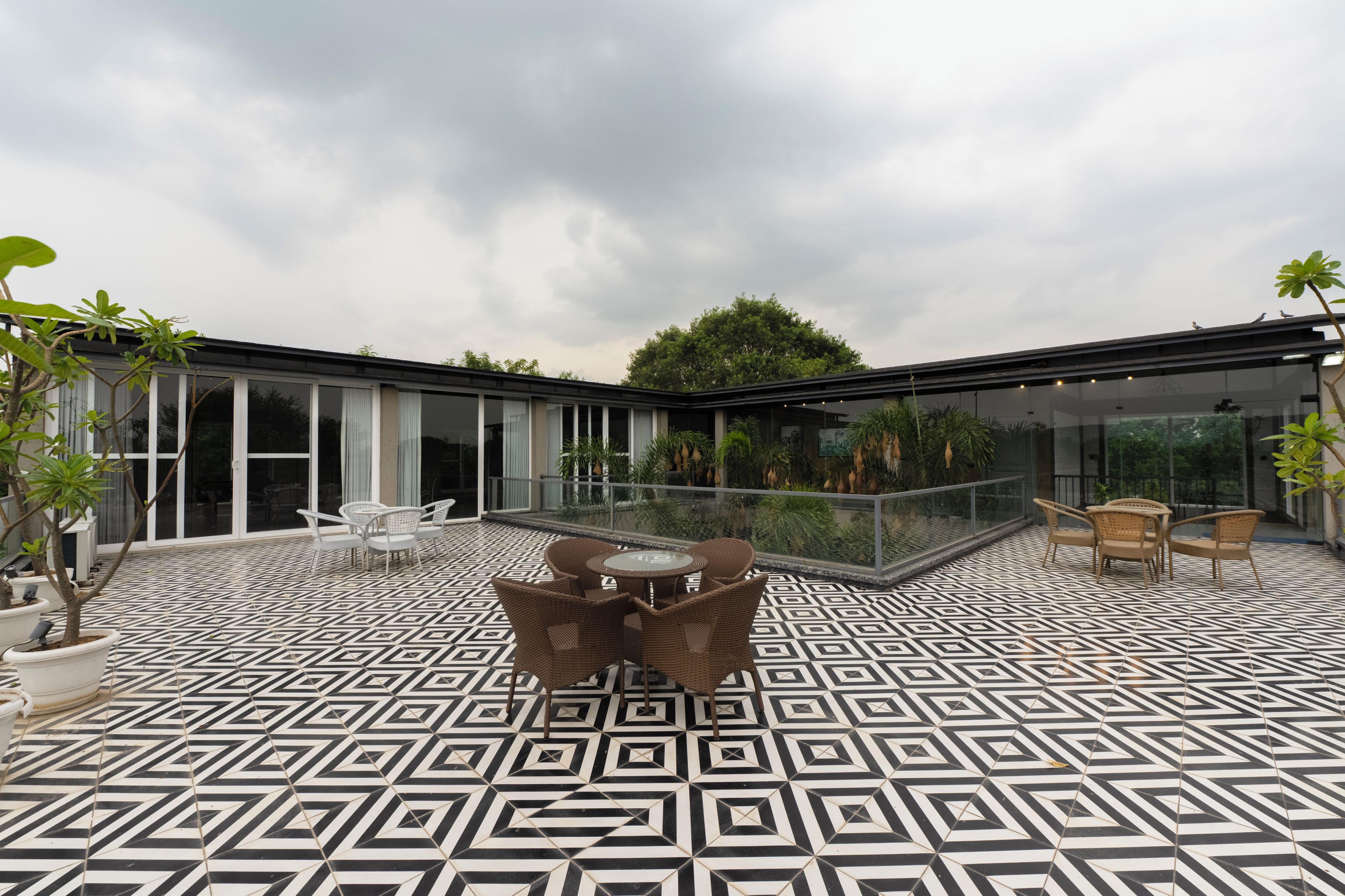 A modern outdoor patio with geometric patterned flooring, a central round table, and seating arrangements.