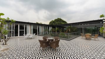 A modern outdoor patio with geometric patterned flooring, a central round table, and seating arrangements.
