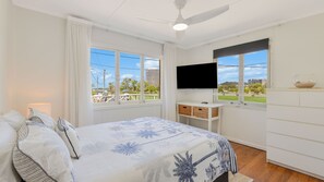 A bedroom with a bed, a television, a window with a view of the outdoors, and a ceiling fan. - Rainbow Beach Shack - Cute and Cozy Unit Between the Tweed River and Rainbow Bay - Min. 1 Night Stays - Linen Provided (Tweed Heads)