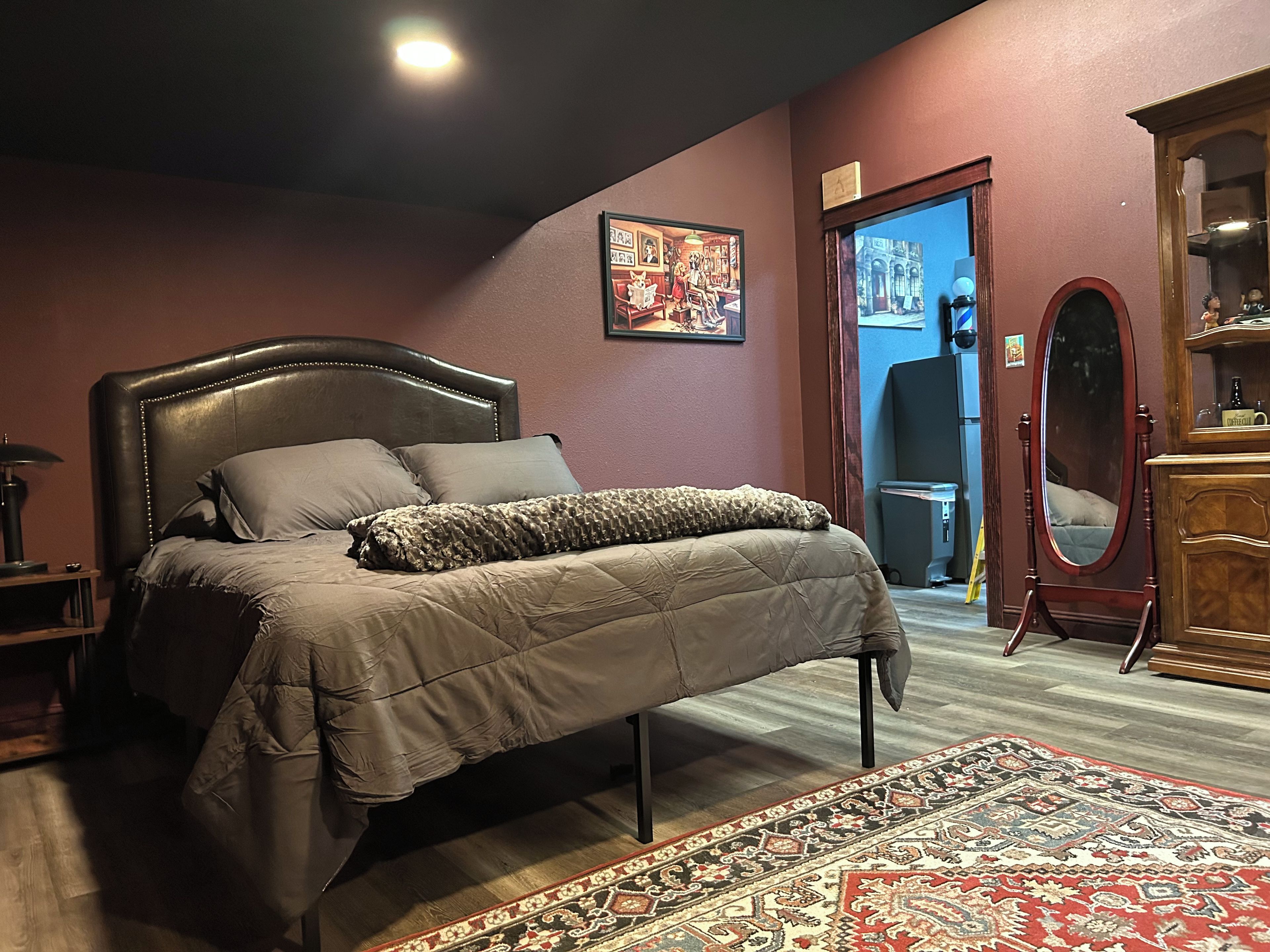Une chambre à coucher avec un lit, une commode en bois, un miroir et un tapis.