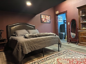 A bedroom with a bed, a wooden dresser, a mirror, and a rug.