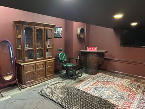 A room with a wooden cabinet, a green chair, a rug, and a barrel with an 'ON AIR' sign.