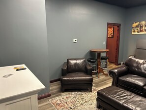 A living room with a white table, two leather sofas, a patterned rug, and a small round table with stools.