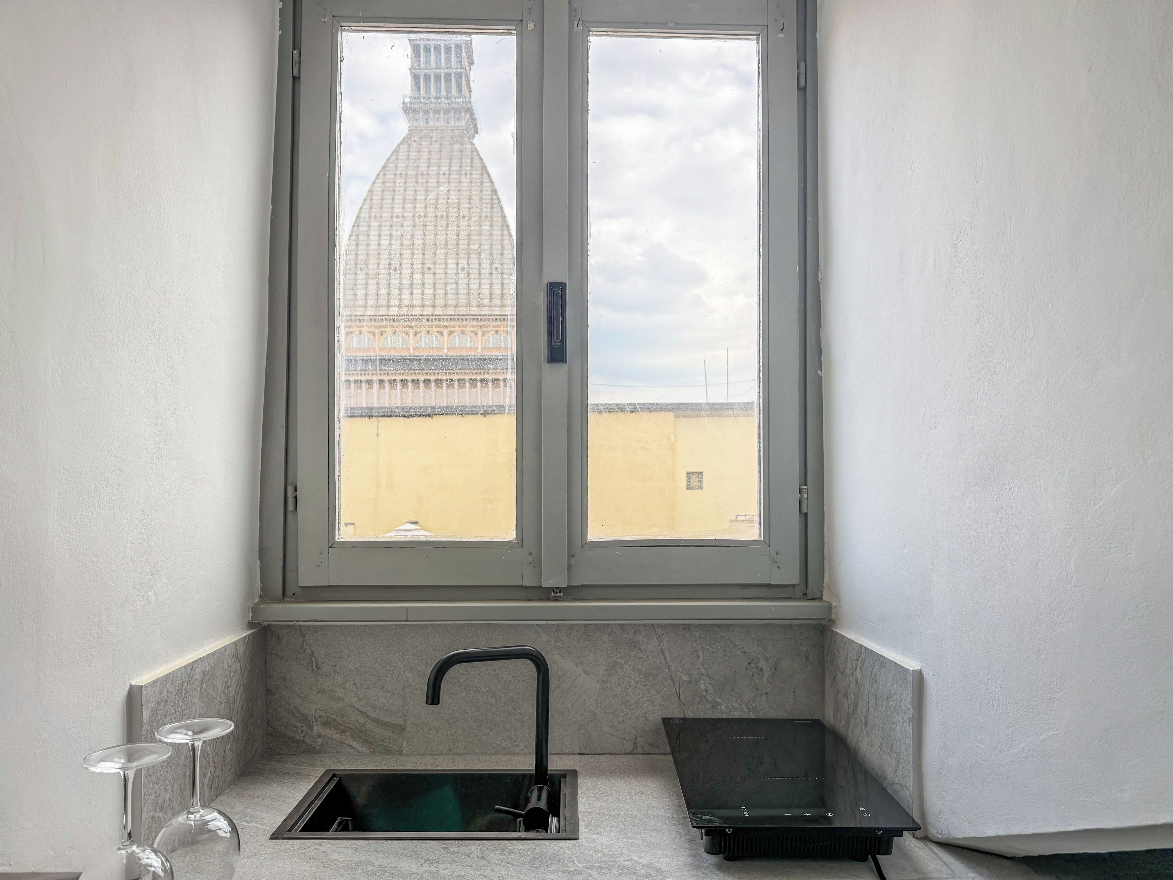 A bathroom with a window, a sink, and two glasses.