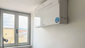 A room with a window, a wall-mounted air conditioner, and a security camera.