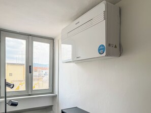 Una habitación con ventana, aire acondicionado de pared y una cámara de seguridad.