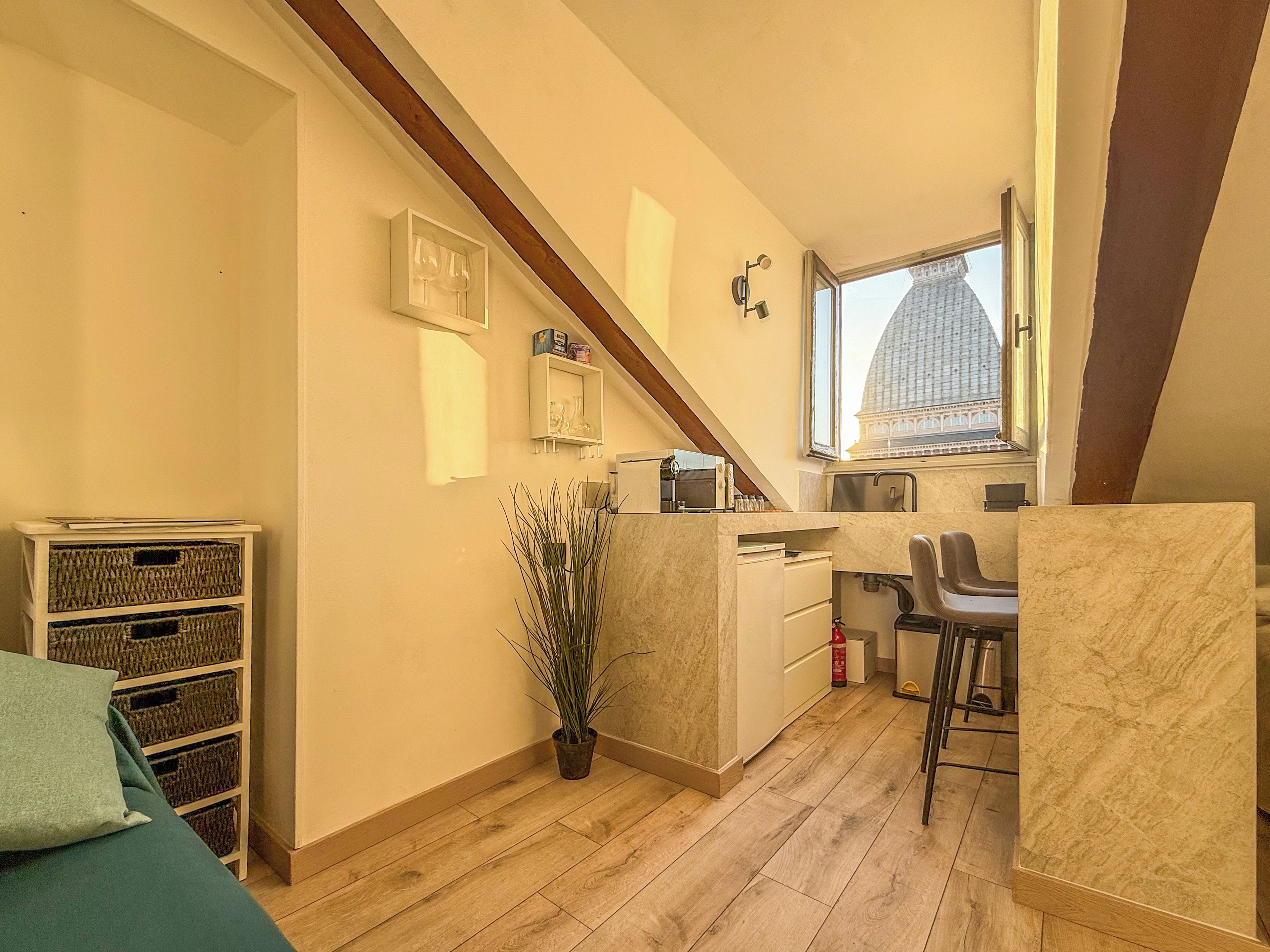 Una cocina compacta con ventana, una planta en maceta y un pequeño comedor.