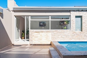 A modern house with a swimming pool, a glass door entrance, and a stone wall. - 5BR Sea Point Oasis: Main House + Flatlet - Solar Powered - Heated Pool & Garage (Cape Town)