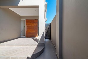 Un immeuble résidentiel moderne doté d’un toit plat, d’une porte en bois et d’un hall d’entrée carrelé.