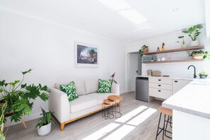 A modern living space with a sofa, coffee table, and kitchen area including a microwave and toaster. - 5BR Sea Point Oasis: Main House + Flatlet - Solar Powered - Heated Pool & Garage (Cape Town)