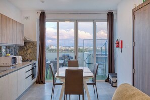 A modern kitchen with a dining area and a large window overlooking a cityscape. - 2BR Penthouse, Private Rooftop Pool & Views - WIFI (Żurrieq)