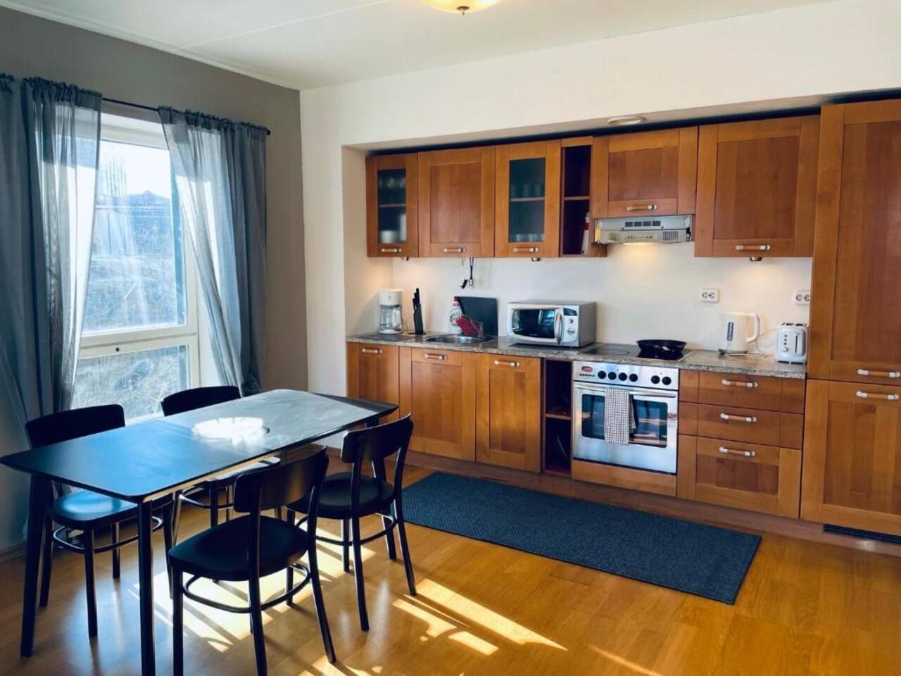 Une cuisine compacte dotée de meubles en bois, d’un four à micro-ondes, d’une cuisinière et d’une table à manger avec des chaises.