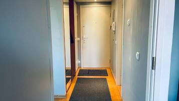 A narrow hallway with a carpeted floor leading to a door.