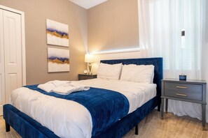 Une chambre d’hôtel avec un lit, une table de chevet, une lampe et des œuvres d’art accrochées au mur.