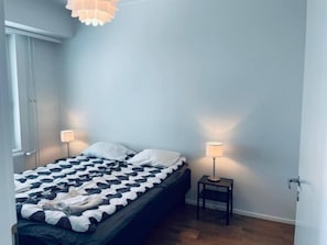 Un dormitorio con una cama, dos lámparas de noche, una ventana y una puerta.