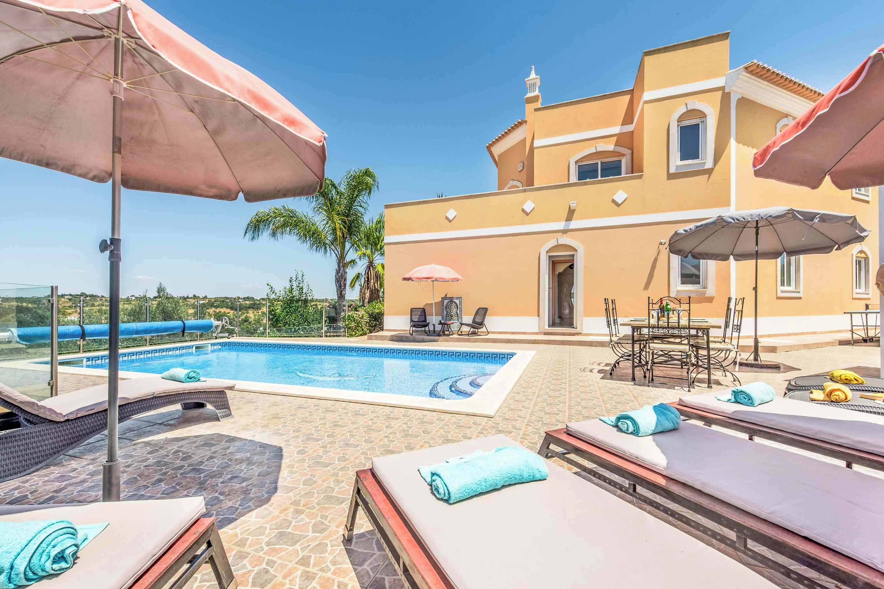 A poolside area with lounge chairs, umbrellas, and a pool.