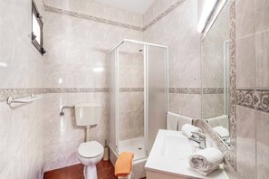 Ein Badezimmer mit Toilette, Dusche und Waschbecken mit Spiegel.