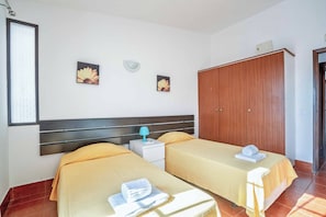 Ein Hotelzimmer mit zwei Betten, einem Kleiderschrank und Bildern an der Wand.