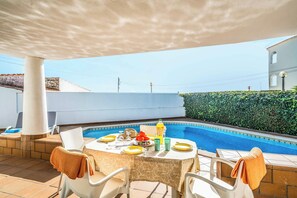 Ein überdachter Außenbereich mit Pool, Esstisch, Stühlen und gedecktem Tisch.
